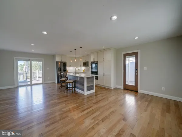 a kitchen with stainless steel appliances granite countertop a stove top oven a sink dishwasher a dining table and chairs with wooden floor