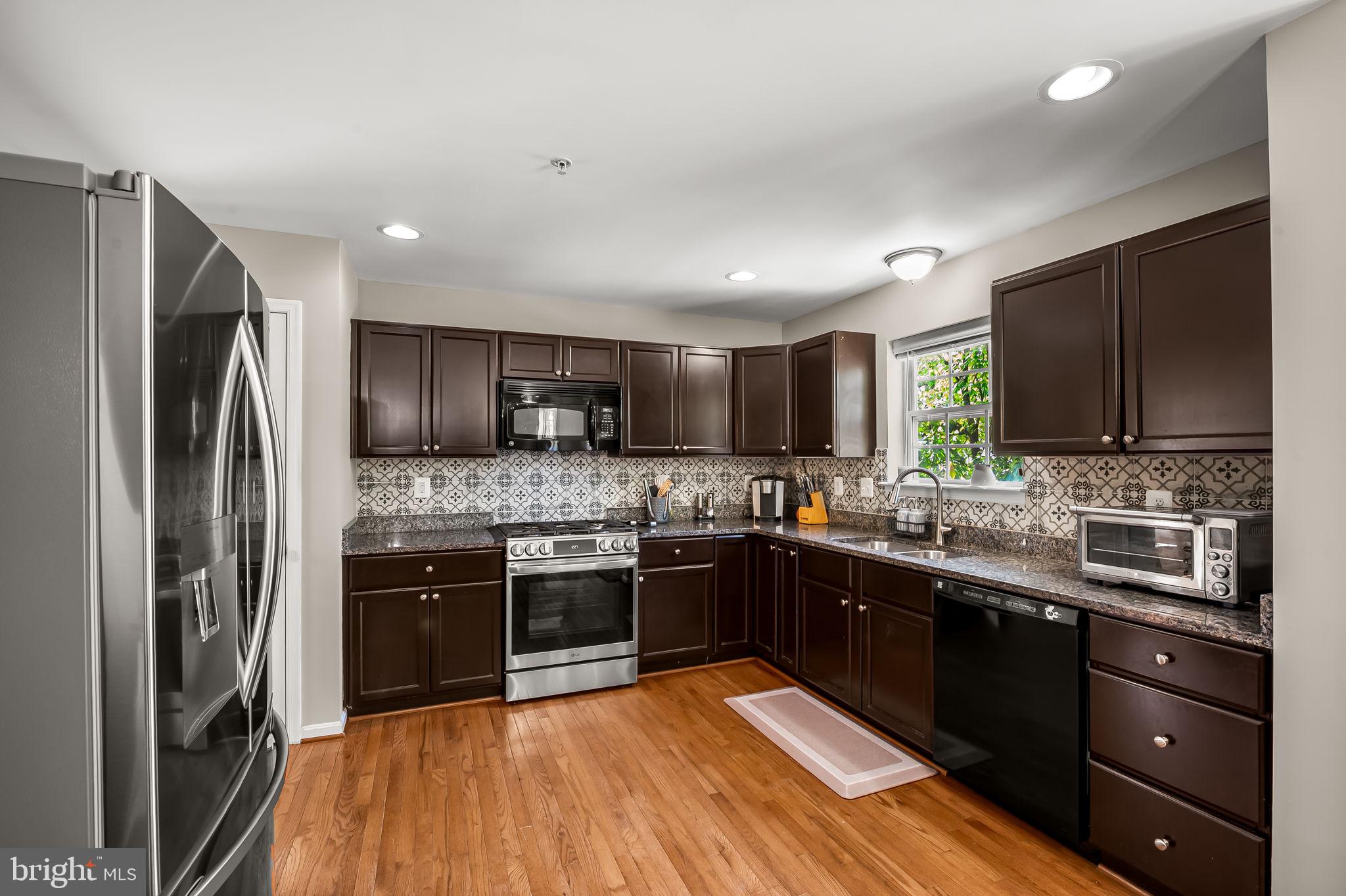 6008 Hanover Road Elkridge, MD 21075 - Photo 10 of 36 a kitchen with stainless steel appliances granite countertop a stove top oven a sink dishwasher a refrigerator and cabinets with wooden floor