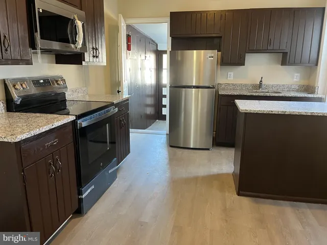 a kitchen with a sink a microwave a refrigerator and cabinets