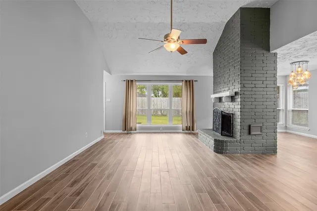 an empty room with wooden floor fireplace and windows