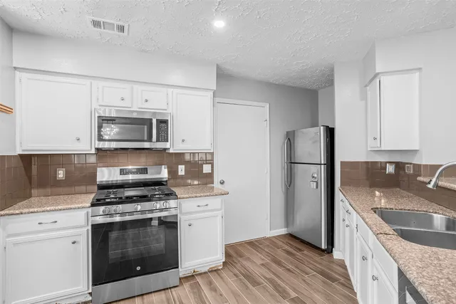 a kitchen with granite countertop a sink stove and refrigerator