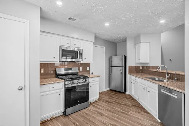 a kitchen with granite countertop a stove sink and refrigerator
