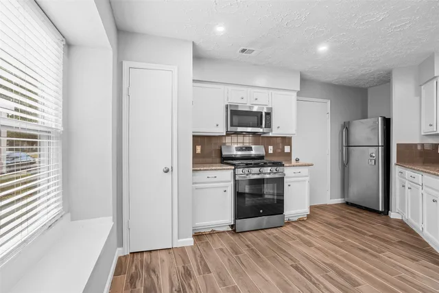 a kitchen with a refrigerator stove and wooden floor
