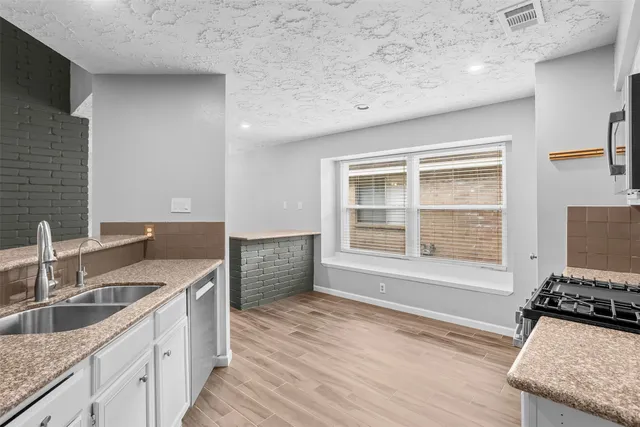 a kitchen with granite countertop a sink wooden floor and a stove top oven