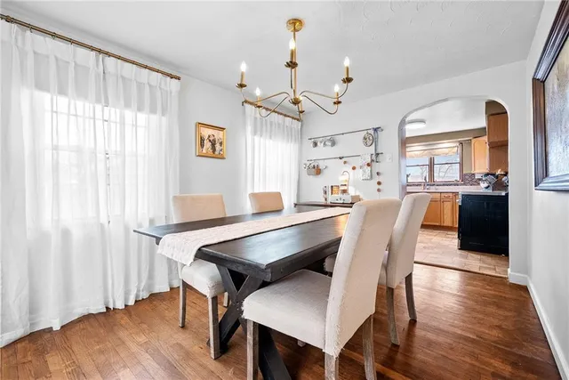 a dining room with wooden floor a chandelier a wooden table and chairs