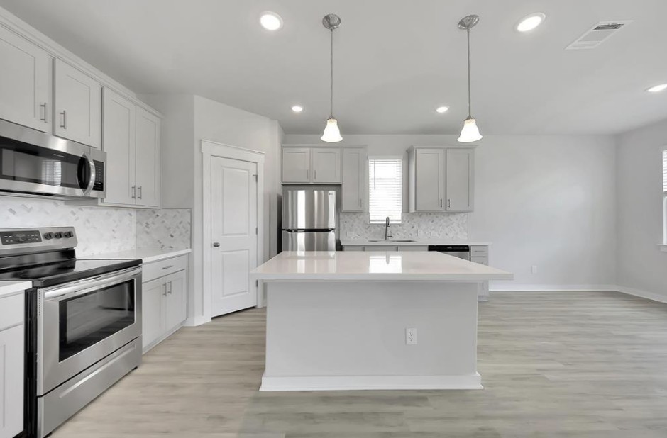 300 Old Trinity Way Georgetown, TX 78628 - Photo 4 of 16 Kitchen featuring stainless steel appliances, a center island, backsplash, and light wood-type flooring