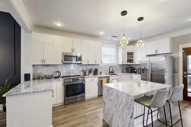 a kitchen with stainless steel appliances granite countertop a sink stove refrigerator and microwave