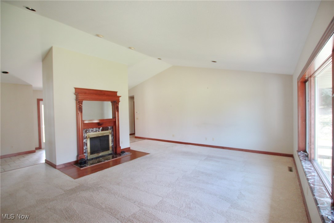1031 Georgetown Road Salem, OH 44460 - Photo 6 of 31 Unfurnished living room featuring a wealth of natural light, a tiled fireplace, carpet flooring, and vaulted ceiling