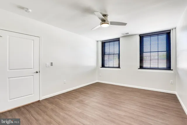 a view of empty room with wooden floor and fan