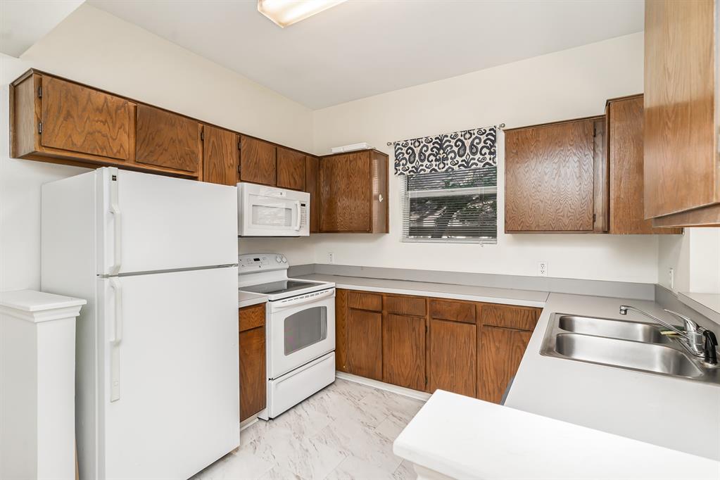 3329 Rosedale Avenue, Unit 21 University Park, TX 75205 - Photo 9 of 24 Kitchen featuring white appliances, light marble finish floors, brown cabinets, and light countertops