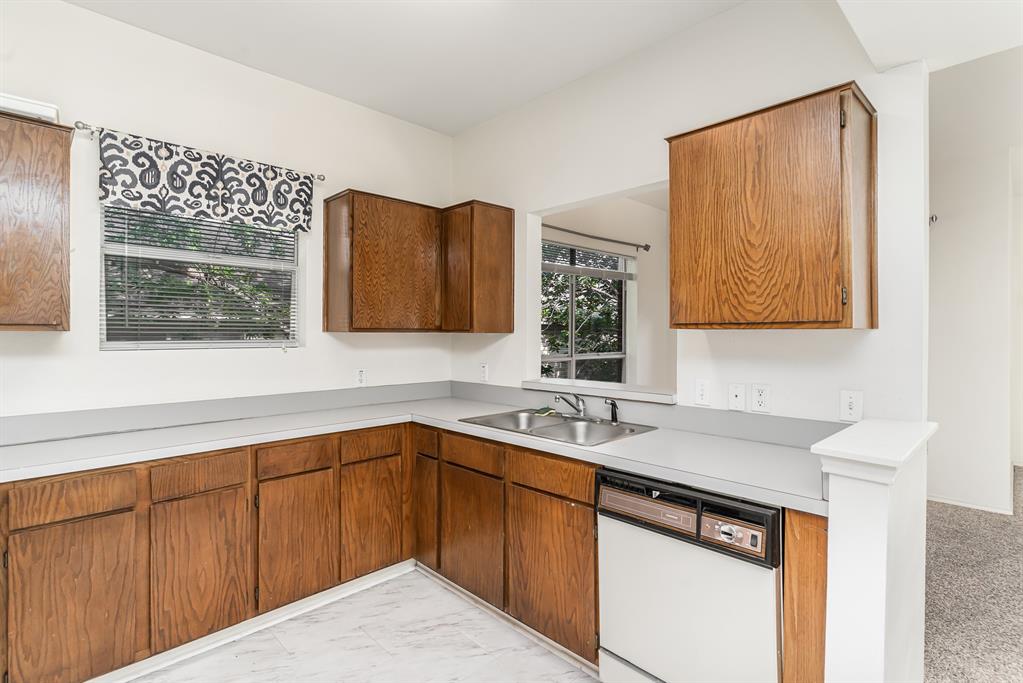 3329 Rosedale Avenue, Unit 21 University Park, TX 75205 - Photo 10 of 24 Kitchen with dishwasher, light countertops, light marble finish floors, and brown cabinetry