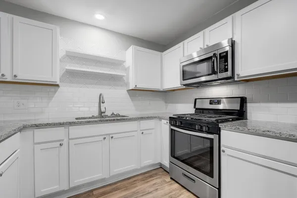 a kitchen with stainless steel appliances granite countertop white cabinets a sink and dishwasher