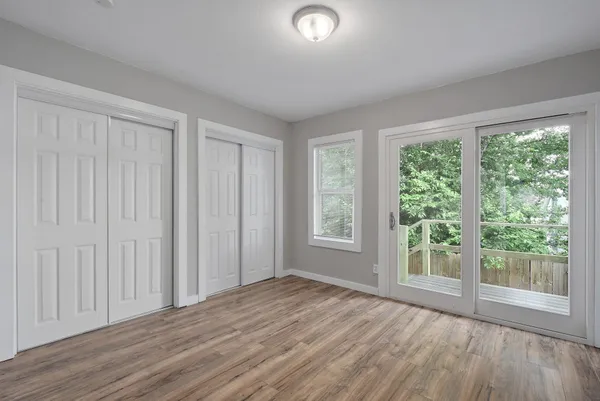 an empty room with wooden floor and windows