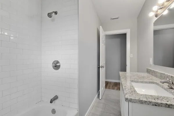 a bathroom with a granite countertop sink a mirror and shower
