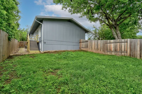 a view of backyard of house with wooden fence