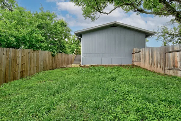 a brick house with a small yard plants and large tree
