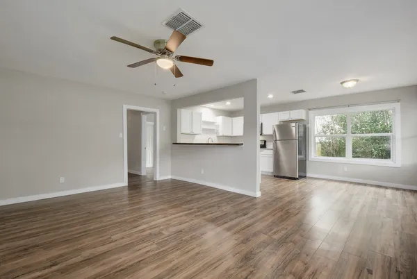 a view of an empty room with a window and wooden floor