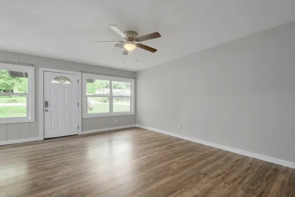 a view of empty room with wooden floor and fan