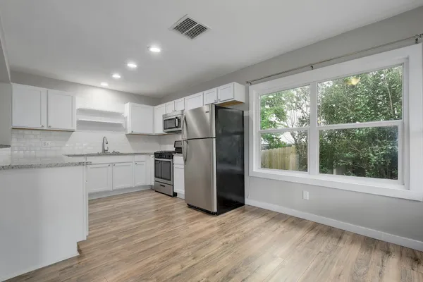 a kitchen with a refrigerator cabinets and wooden floor