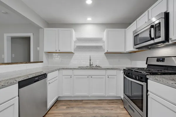 a kitchen with stainless steel appliances granite countertop a stove a sink and a microwave