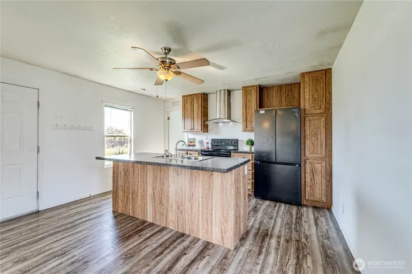 a kitchen with stainless steel appliances granite countertop a refrigerator a sink a stove and white cabinets with wooden floor