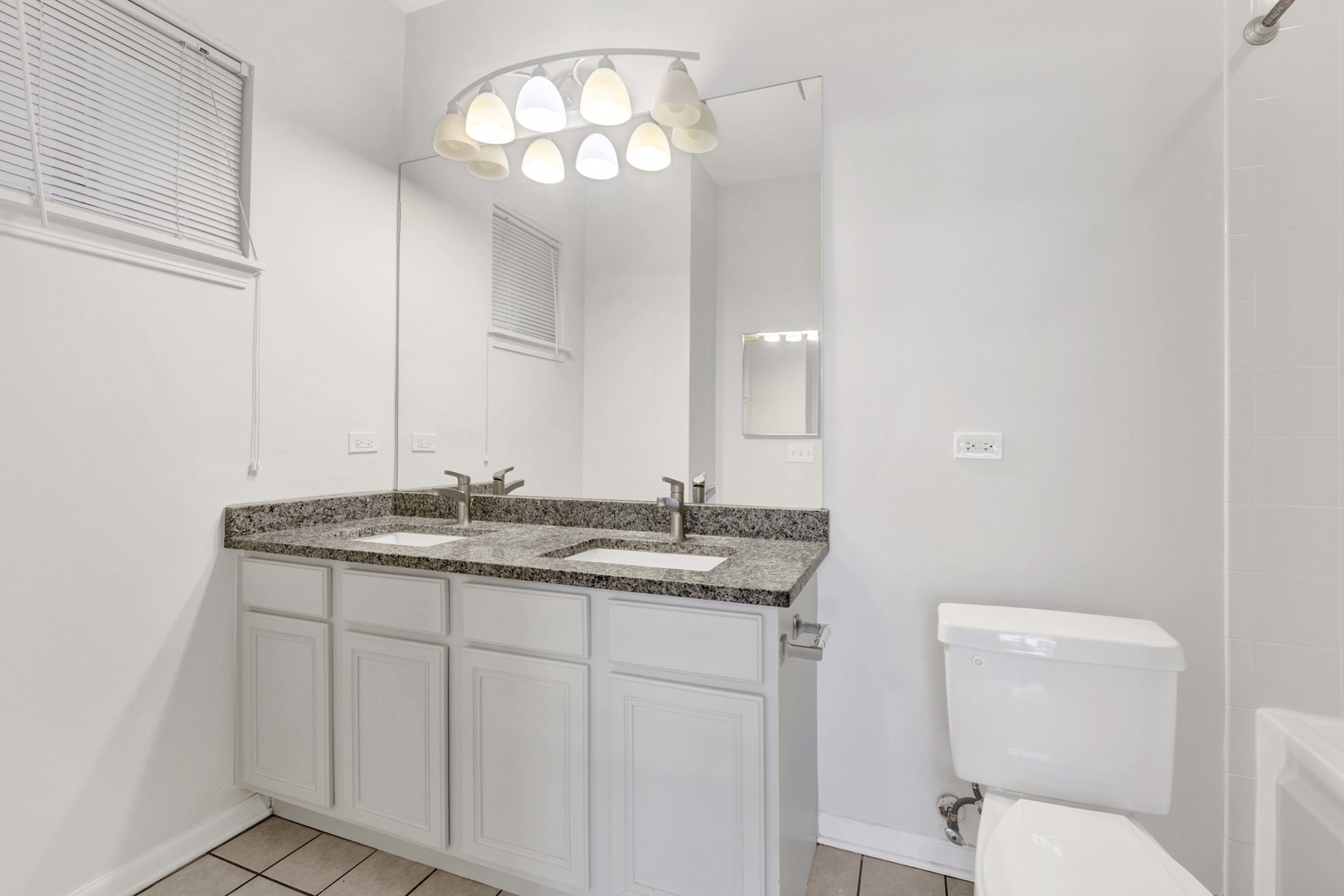 948 West 15th Place, Unit 1B Chicago, IL 60608 - Photo 19 of 59 a bathroom with a granite countertop toilet a sink and a mirror