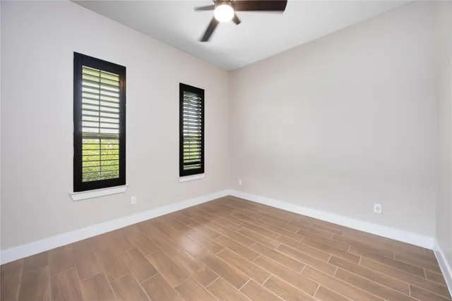 an empty room with windows and fan