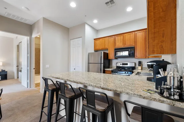 a kitchen with granite countertop a table chairs microwave and refrigerator