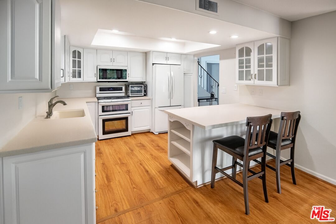 27003 Rio Prado Drive Valencia, CA 91354 - Photo 8 of 40 a kitchen with stainless steel appliances granite countertop a stove top oven a sink dishwasher and a refrigerator with wooden floor