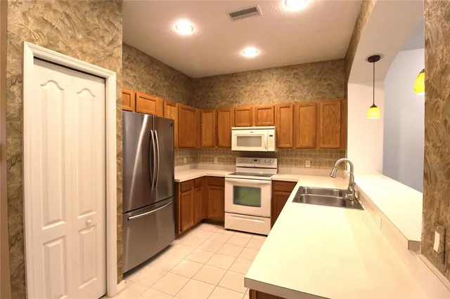 a kitchen with stainless steel appliances granite countertop a refrigerator a stove and a sink