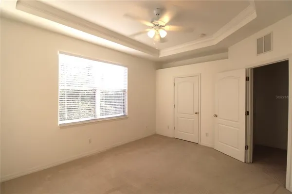 en empty room with windows and chandelier fan