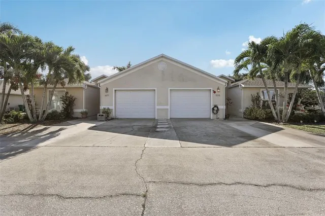 a view of a white house with a yard and palm trees