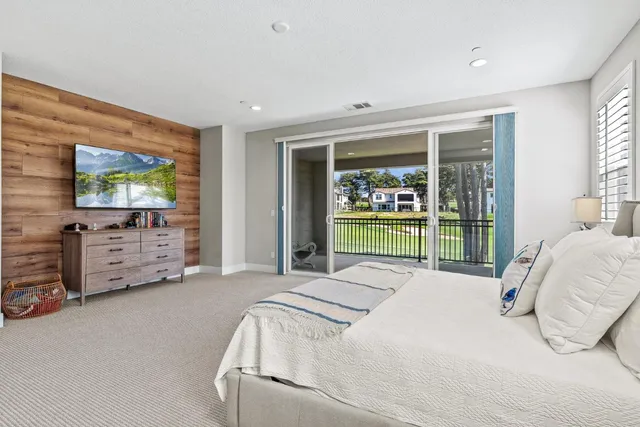 a bed sitting in a bedroom next to a flat tv screen next to a window