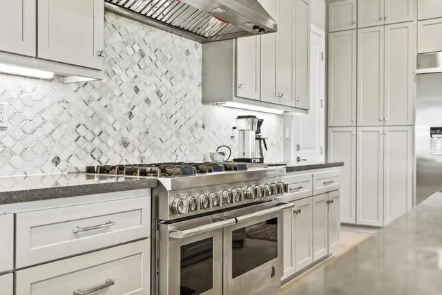 a kitchen with stainless steel appliances granite countertop a stove and a white cabinets