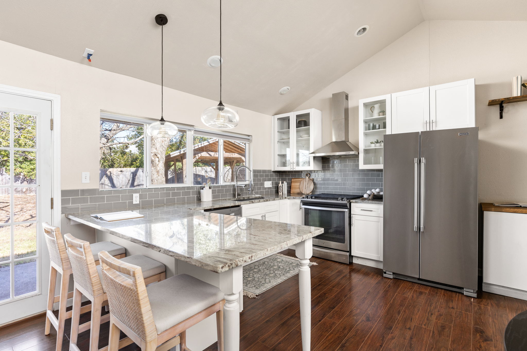 6502 Highpoint Cove Austin, TX 78723 - Photo 14 of 40 Kitchen with white cabinets, stainless steel appliances, light stone counters, a peninsula, and decorative light fixtures