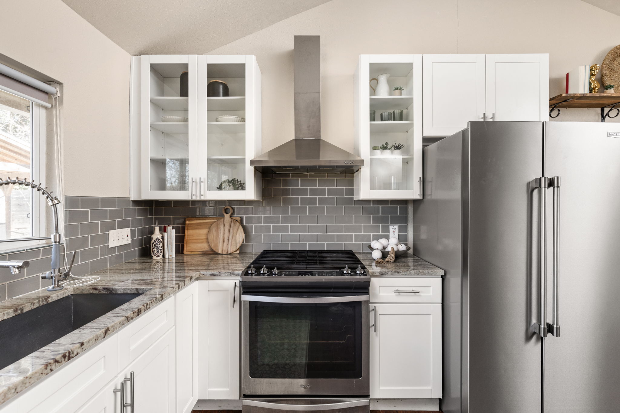 6502 Highpoint Cove Austin, TX 78723 - Photo 18 of 40 Kitchen with stainless steel appliances, white cabinetry, vaulted ceiling, light stone countertops, and glass fronted cabinets