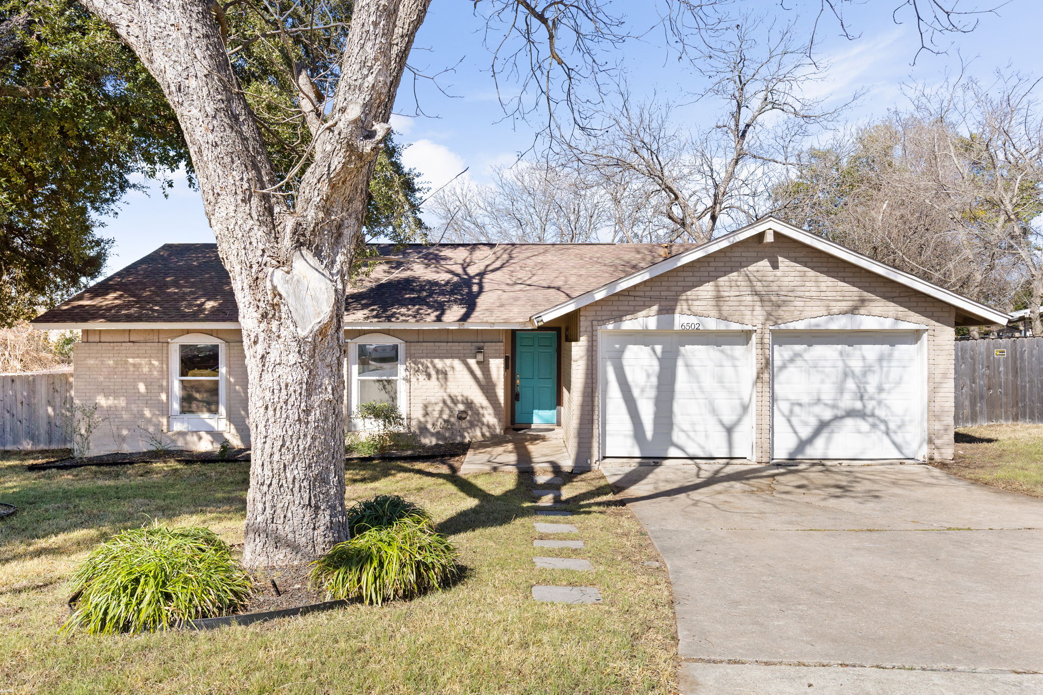 6502 Highpoint Cove Austin, TX 78723 - Photo 2 of 40 Ranch-style home with driveway, brick siding, an attached garage, and roof with shingles