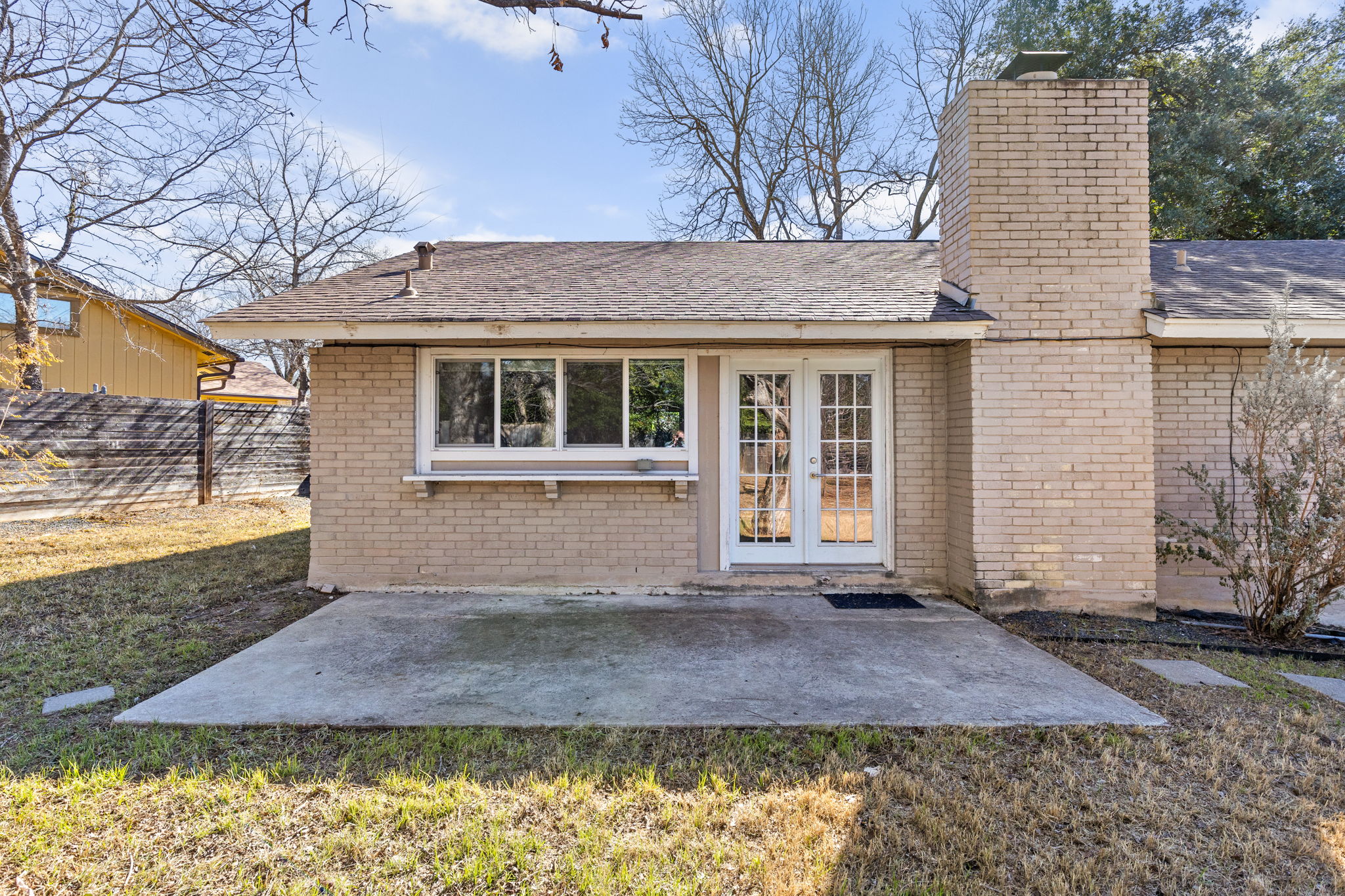 6502 Highpoint Cove Austin, TX 78723 - Photo 30 of 40 Rear view of house featuring french doors, brick siding, a patio, a chimney, and a shingled roof
