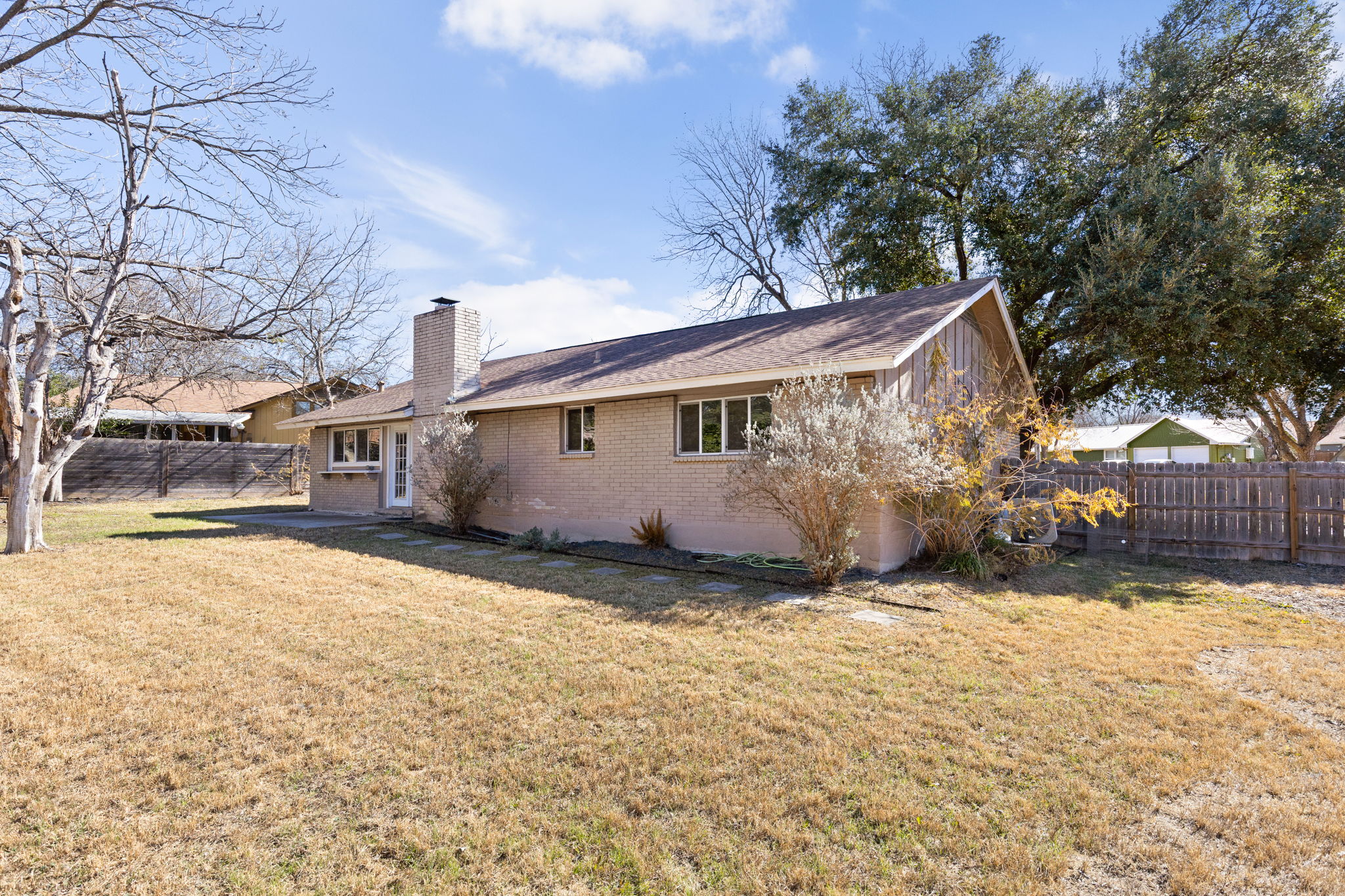 6502 Highpoint Cove Austin, TX 78723 - Photo 39 of 40 Rear view of house with a fenced backyard, brick siding, and a chimney