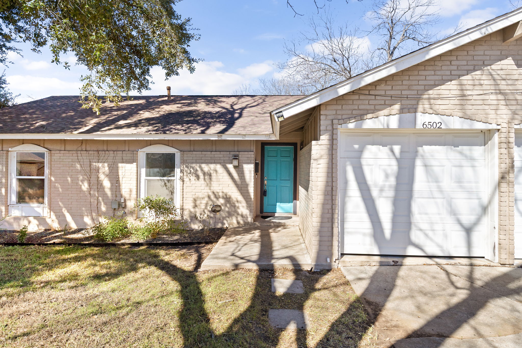 6502 Highpoint Cove Austin, TX 78723 - Photo 4 of 40 Property entrance featuring brick siding, a shingled roof, concrete driveway, an attached garage, and a lawn