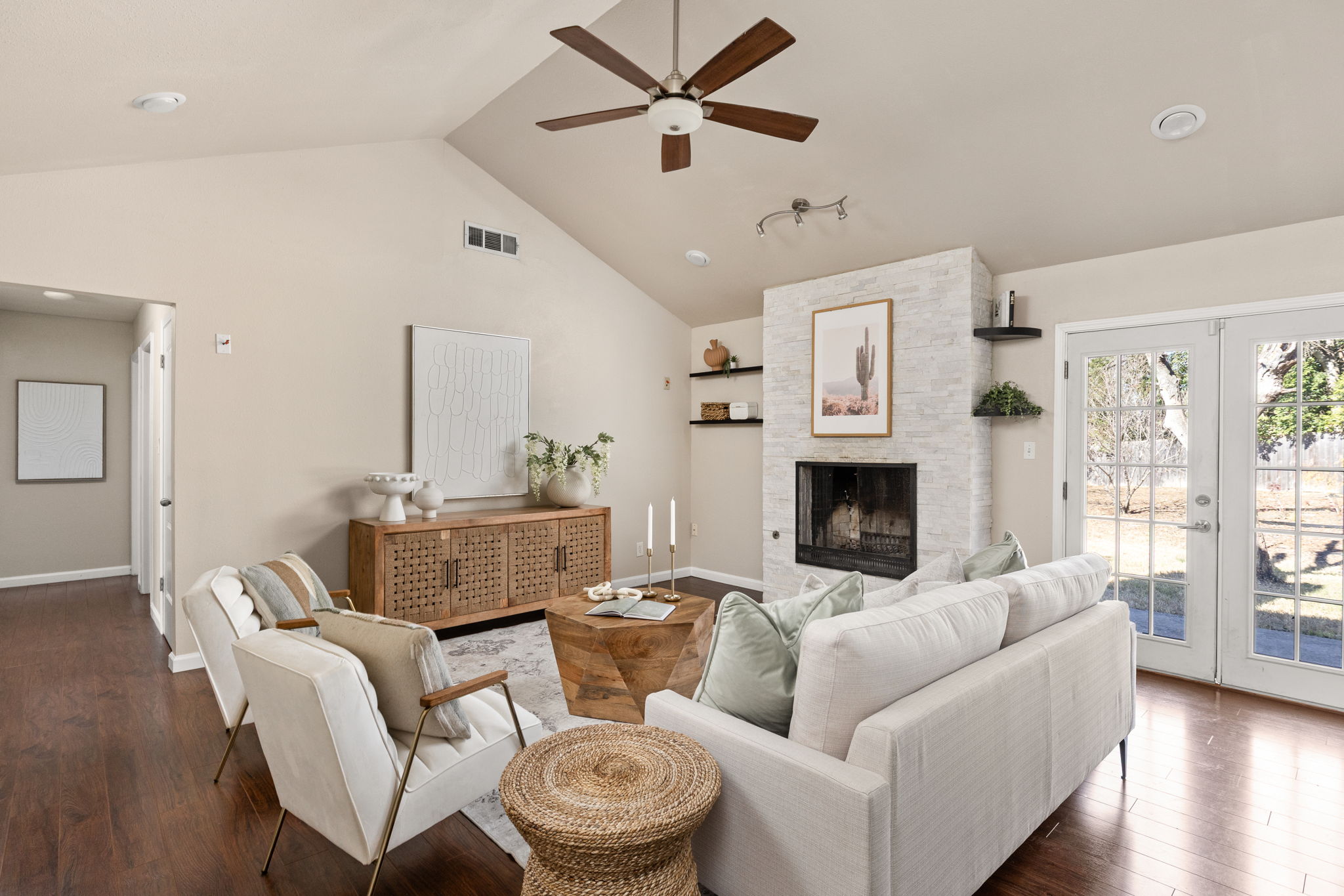 6502 Highpoint Cove Austin, TX 78723 - Photo 9 of 40 Living room with french doors, a ceiling fan, dark wood finished floors, a high ceiling, and a stone fireplace