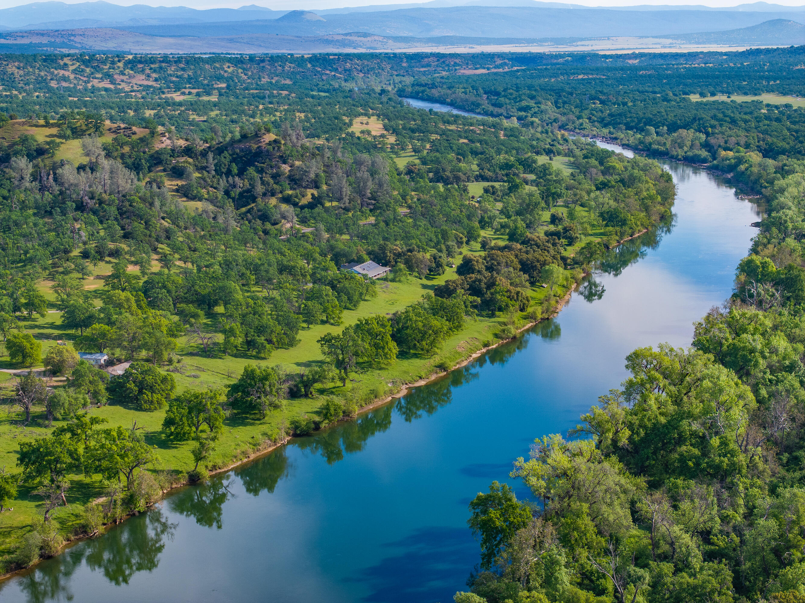 an aerial view of green landscape with trees houses and lake view