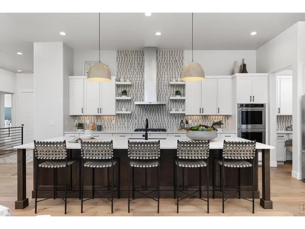 a kitchen with stainless steel appliances kitchen island granite countertop a table chairs and a white cabinets