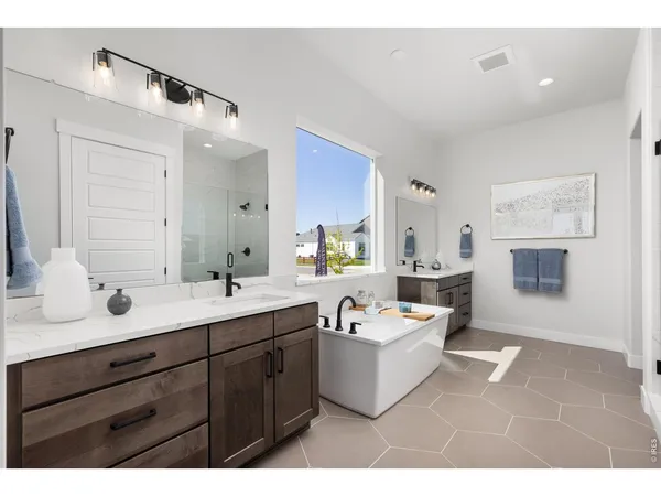 a spacious bathroom with a tub double sink and mirror