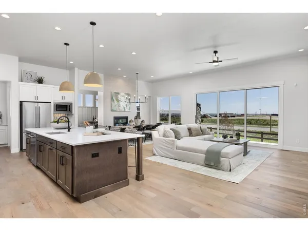 a view of kitchen with stainless steel appliances granite countertop a stove and a view of living room