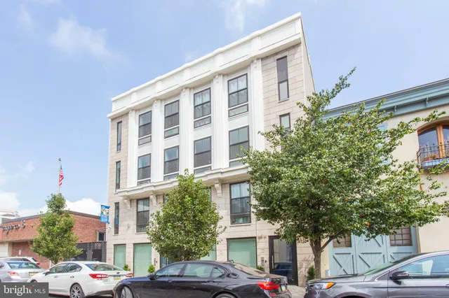 a front view of a building with lot of cars and trees