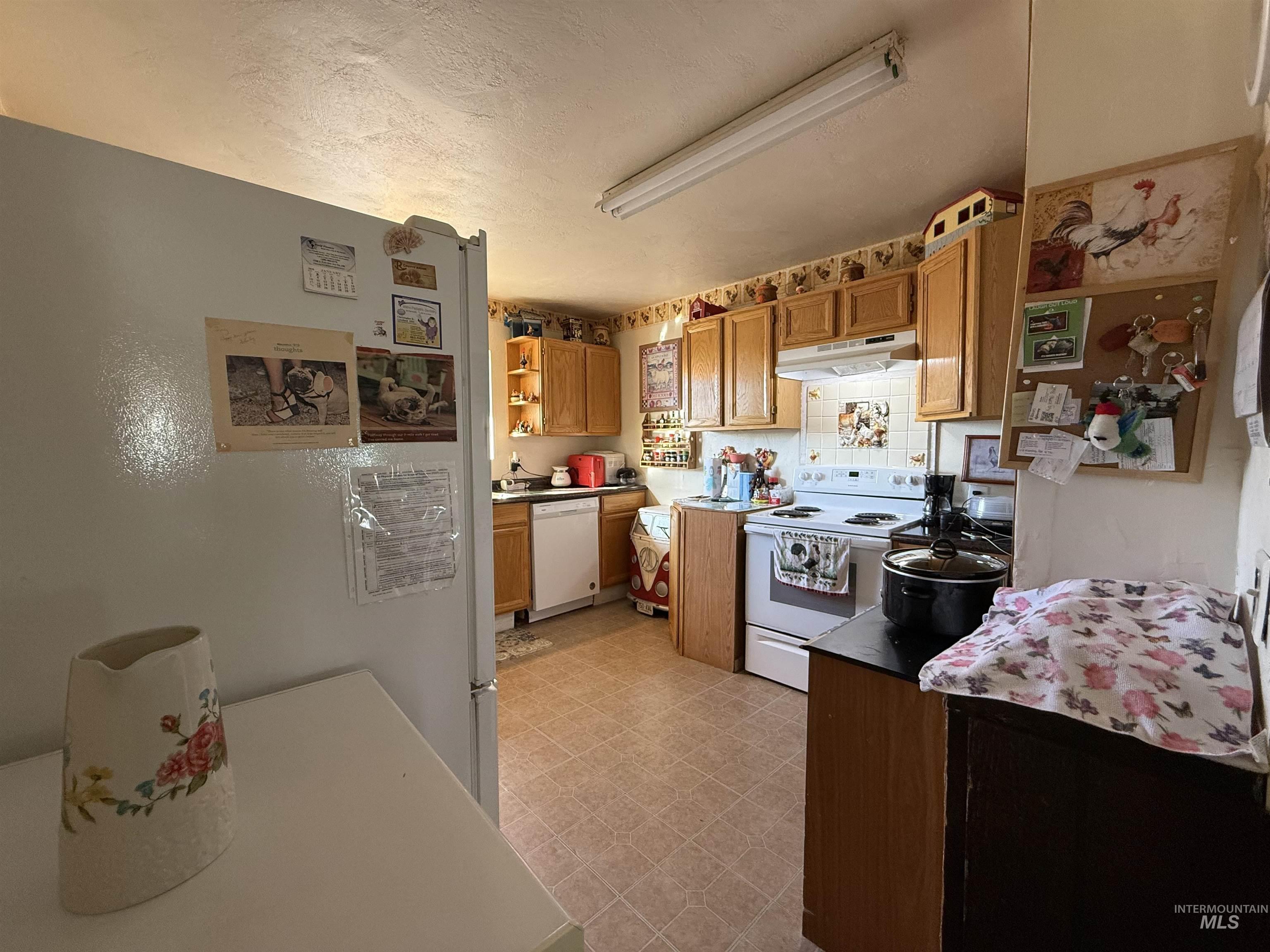 19241 West Homedale Road Caldwell, ID 83607 - Photo 29 of 35 Kitchen with white appliances, light floors, a textured ceiling, wood finish cabinetry, and open shelves