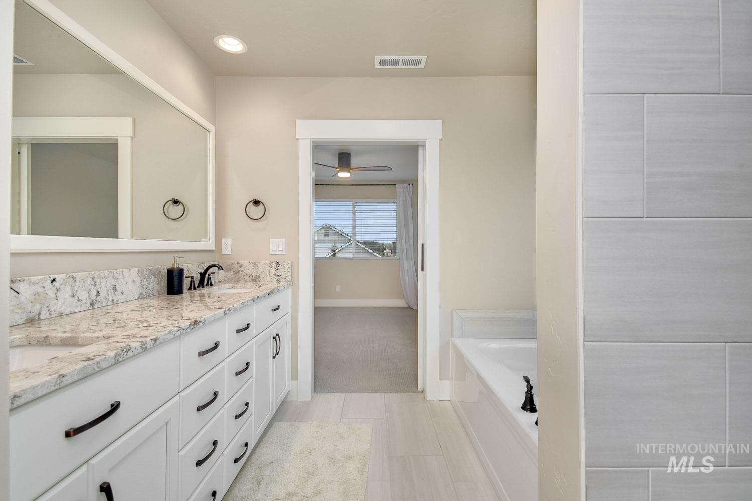 5771 West Daphne Drive Meridian, ID 83646 - Photo 23 of 32 Bathroom with double vanity, a garden tub, and a ceiling fan