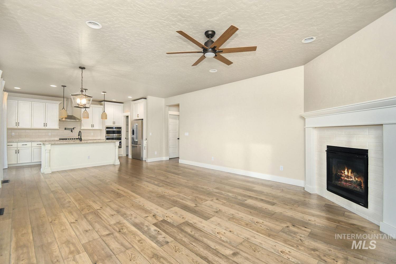 5771 West Daphne Drive Meridian, ID 83646 - Photo 9 of 32 Unfurnished living room featuring recessed lighting, a tile fireplace, light wood-type flooring, a textured ceiling, and ceiling fan