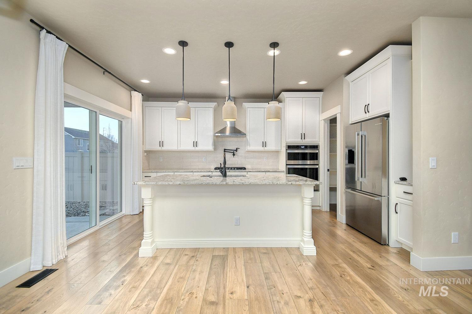 5771 West Daphne Drive Meridian, ID 83646 - Photo 10 of 32 Kitchen with stainless steel appliances, white cabinets, hanging light fixtures, a kitchen island with sink, and recessed lighting